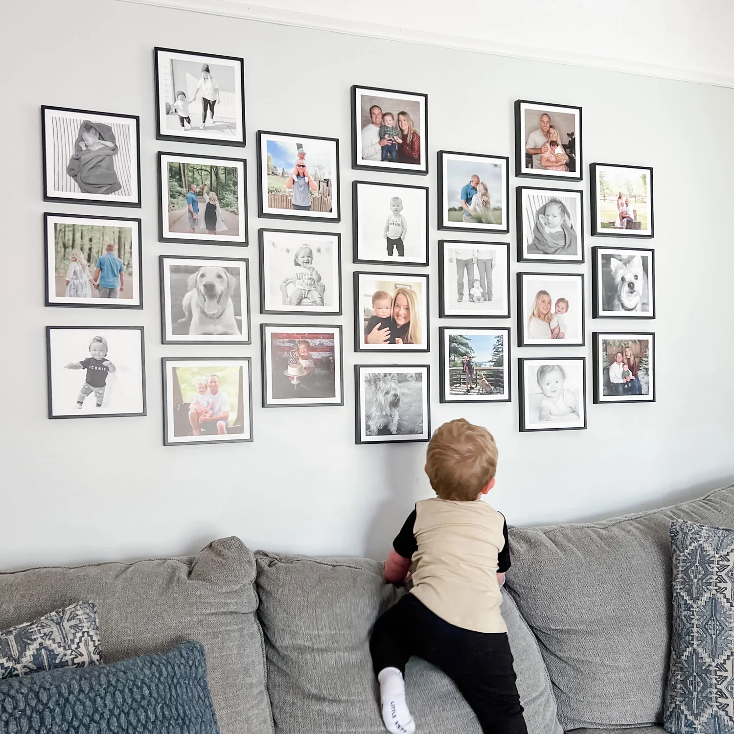 A child looking at an organic arrangement of black Mixtiles family photos