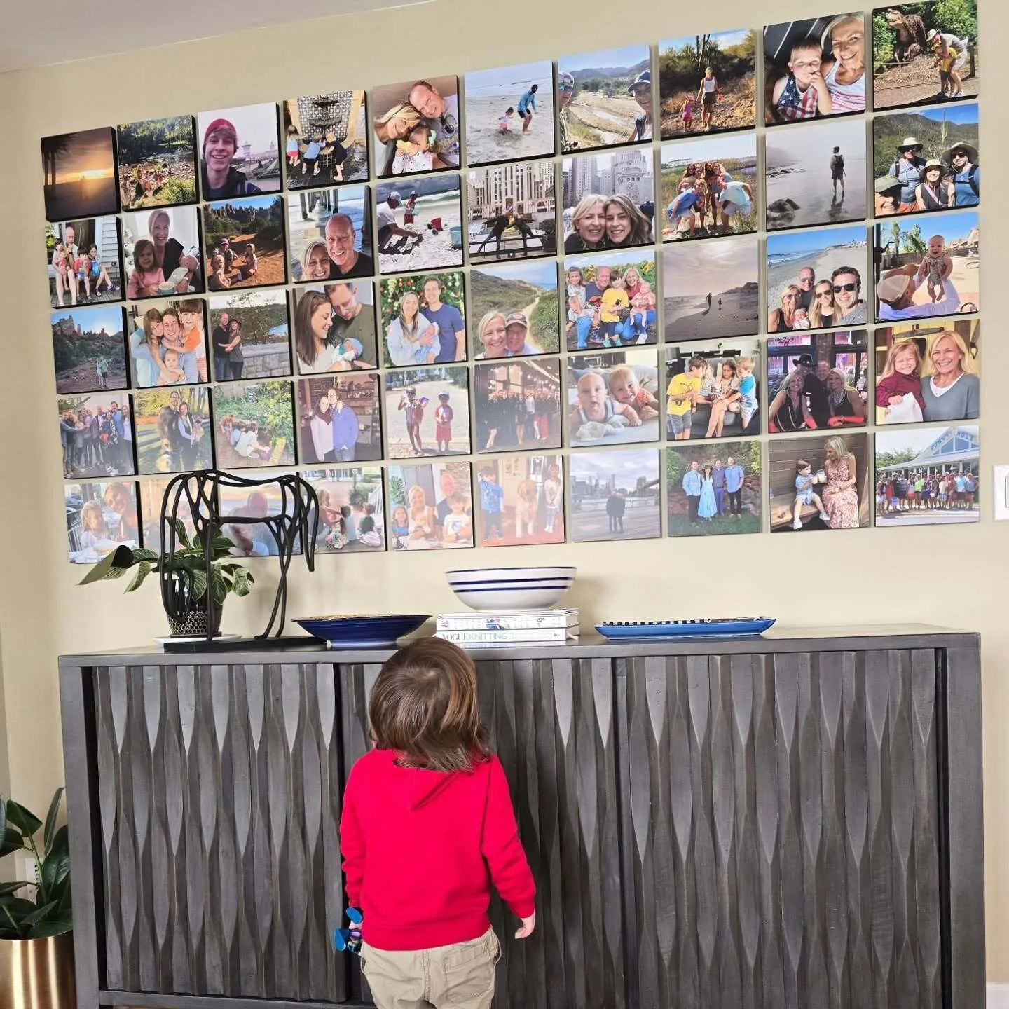 A child looking at a colorful wall of frameless Mixtiles family photos