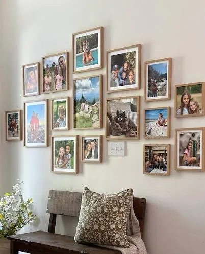 A dense wall of oak-framed Mixtiles photos in several sizes, above a wooden bench